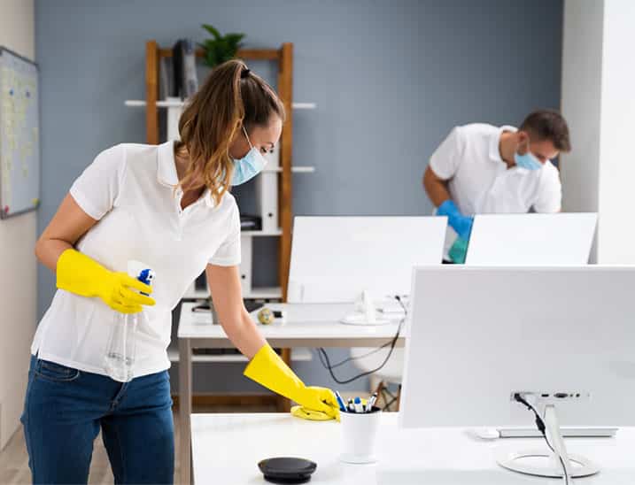 woman, part of a cleaning team, wiping disinfecting a medical office desk